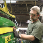 Singcraft employee installing vehicle decal on a John Deere tractor
