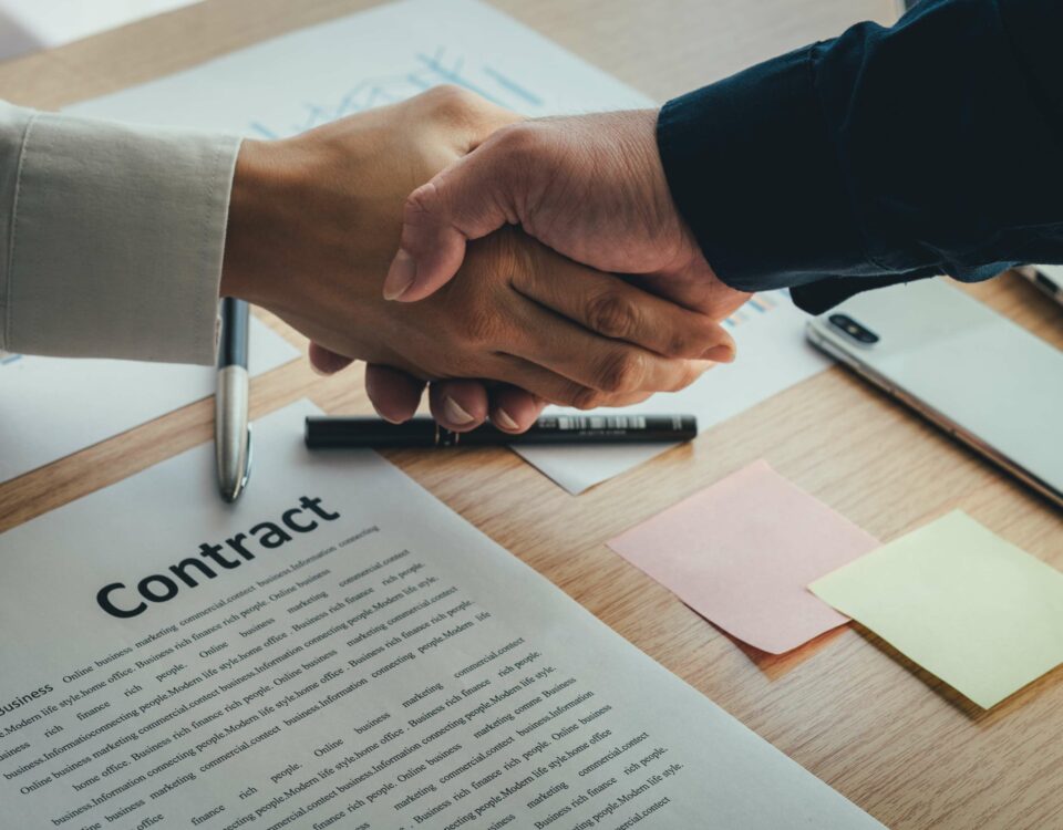 Two people shaking hands over a contract